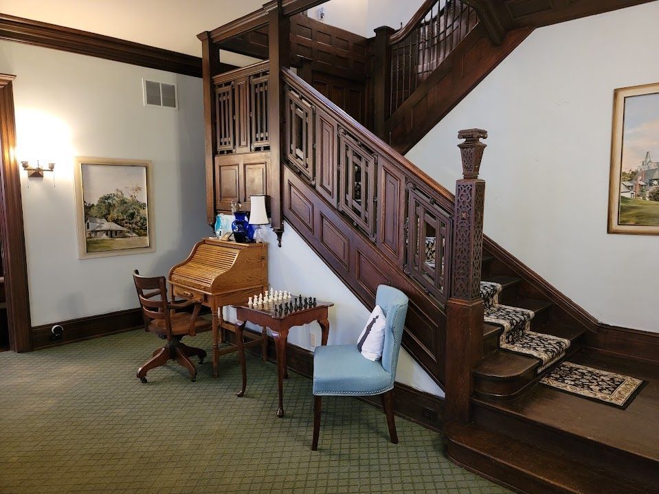 Wooden staircase and desk in a room with paintings and a chessboard.