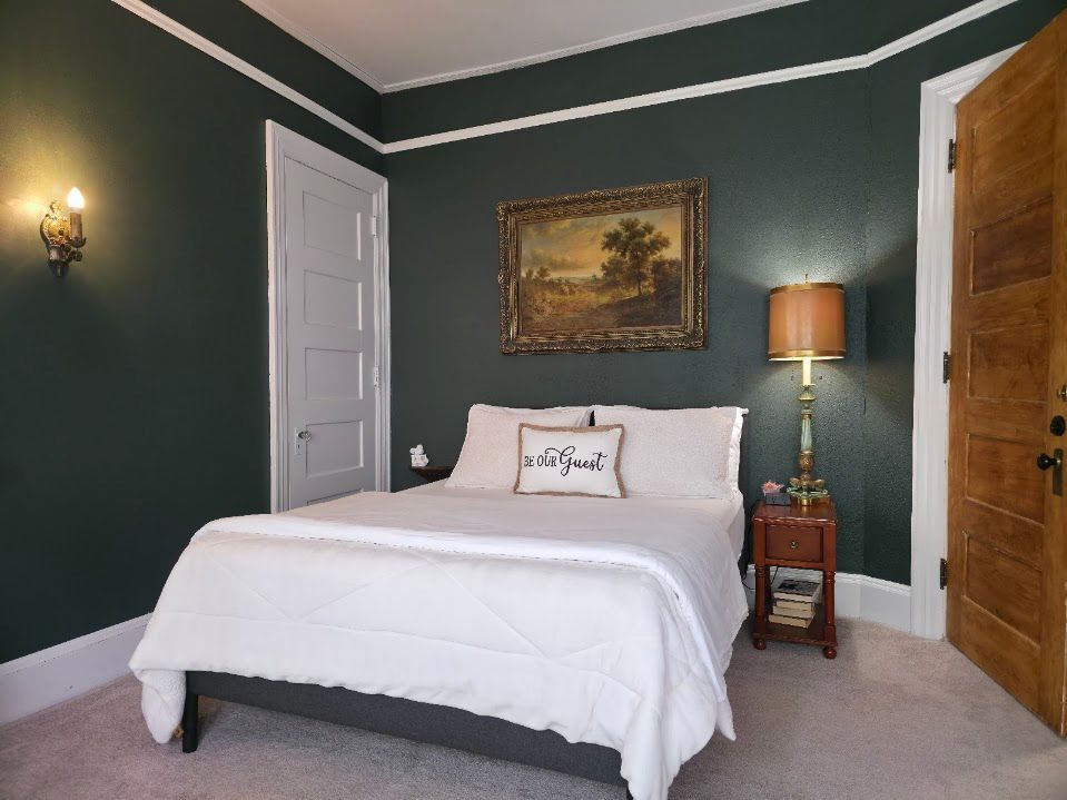 Bedroom with dark green walls, white trim, and a bed with white linens.