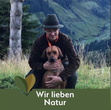 Ein Mann kniet neben einem Hund, unter ihm stehen die Worte „Wir lieben die Natur“