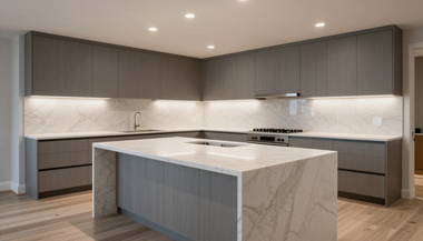 Modern gray kitchen with large marble island, built-in cabinets, and recessed lighting