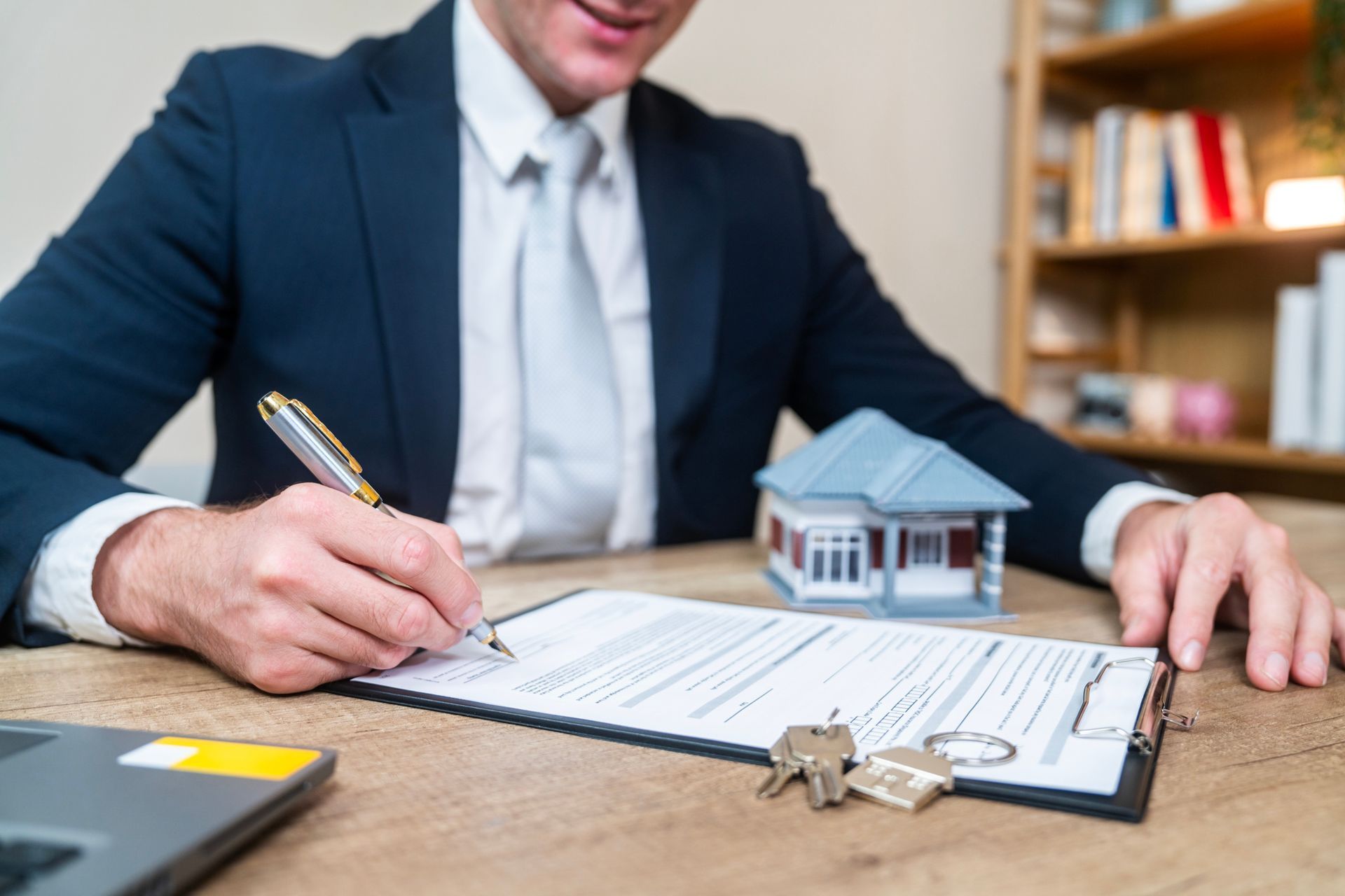 A man in a suit and tie is signing a document. - Real Estate Lawyer in Champaign - Urban, IL