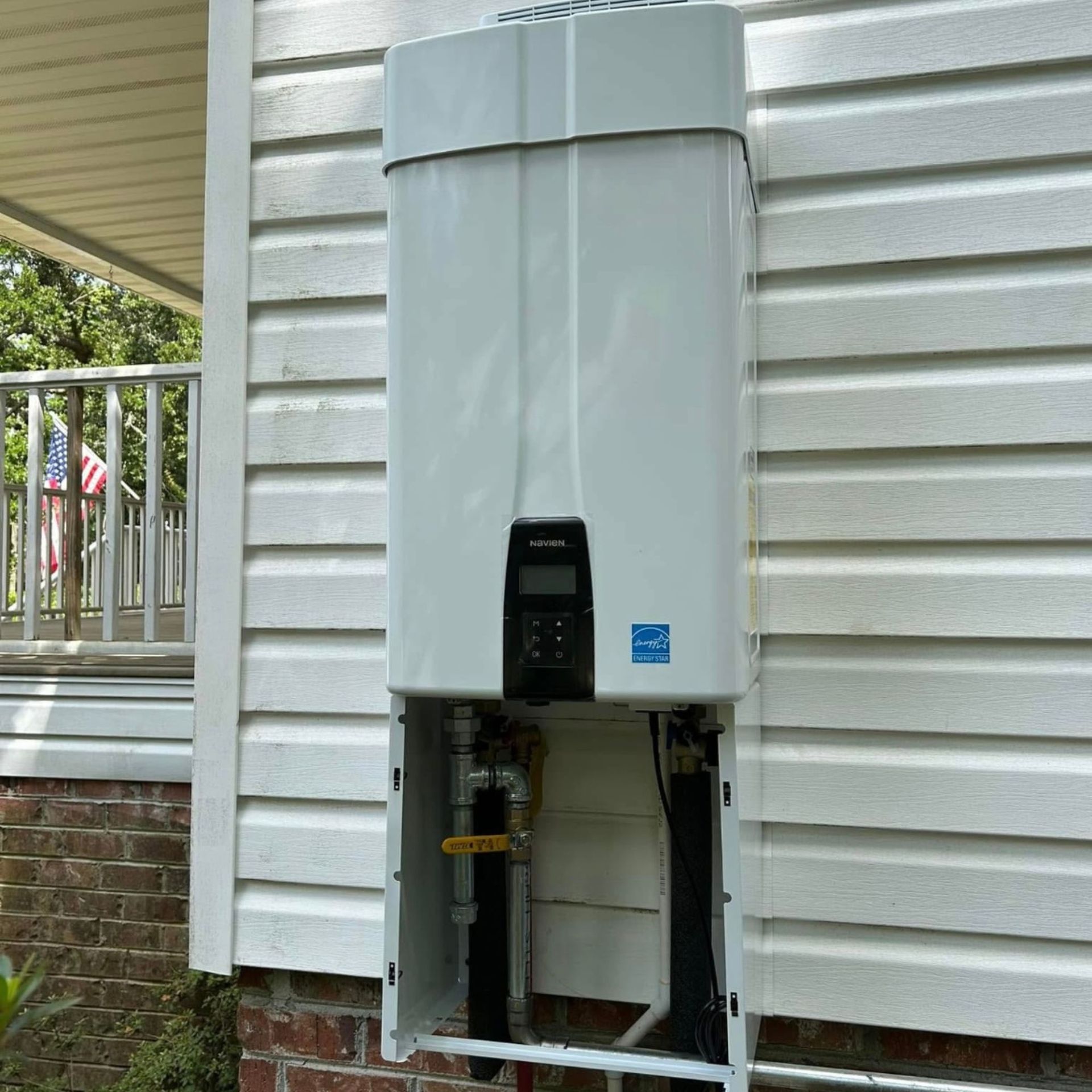 Black River Plumbing & Gas LLC - White, wall-mounted tankless water heater on the side of a house.