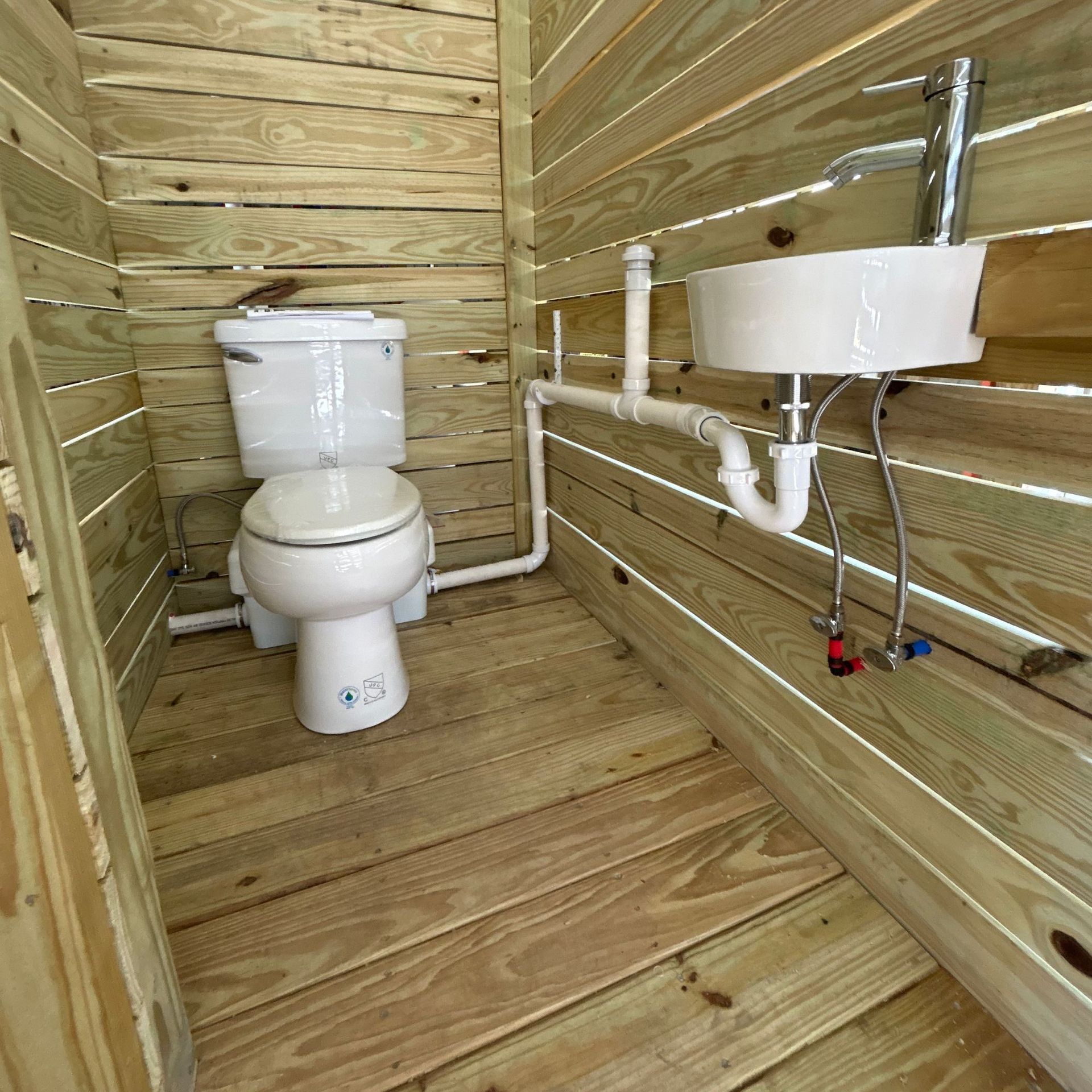 B lack River Plumbing & Gas LLC - Small, unfinished wooden bathroom with toilet and sink.