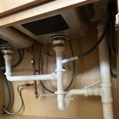 Black River Plumbing & Gas - Under a kitchen sink, plumbing pipes and fixtures: drains, pipes, and connections.