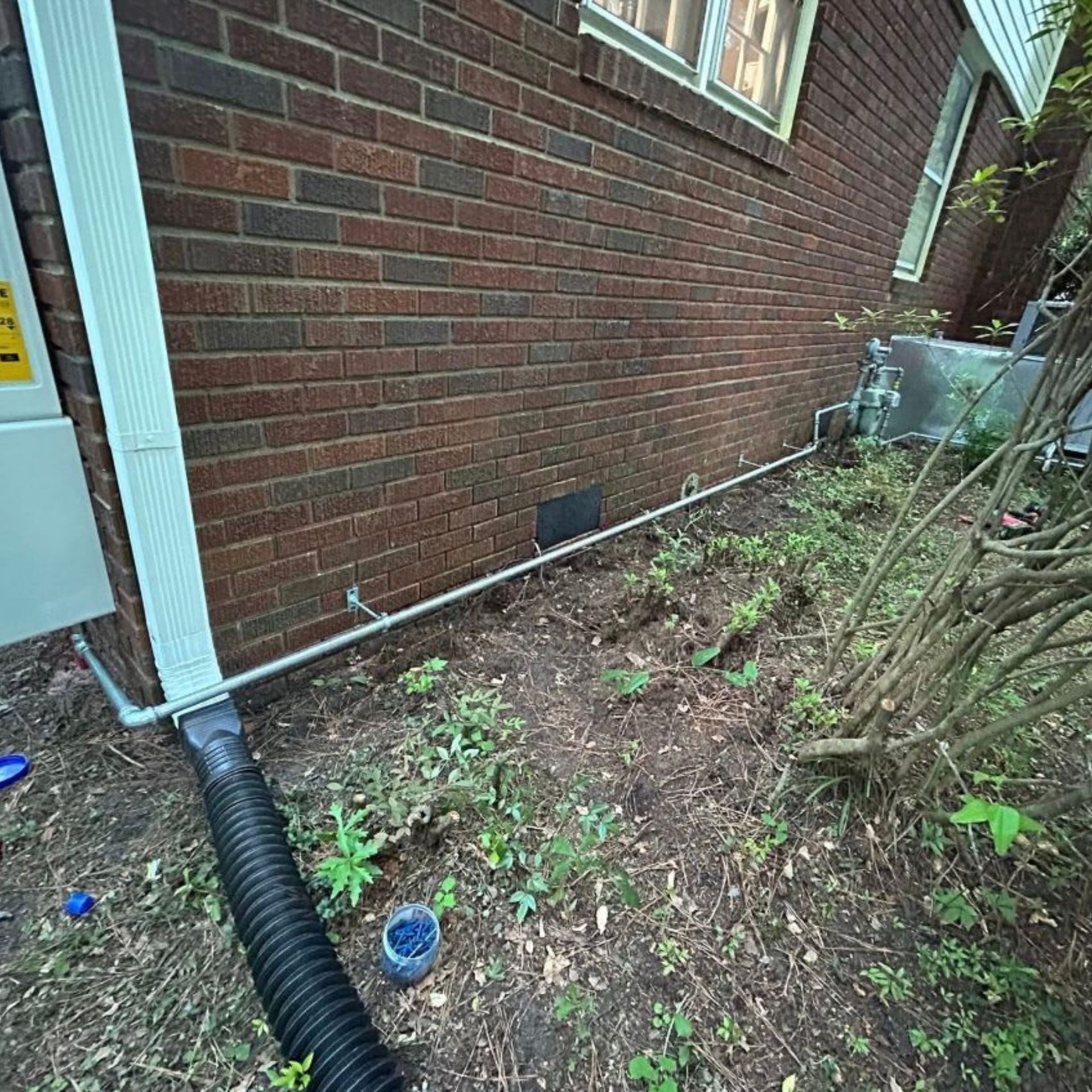 Black River Plumbing & Gas LLC - A brick building with white gutters, a black drainage pipe.