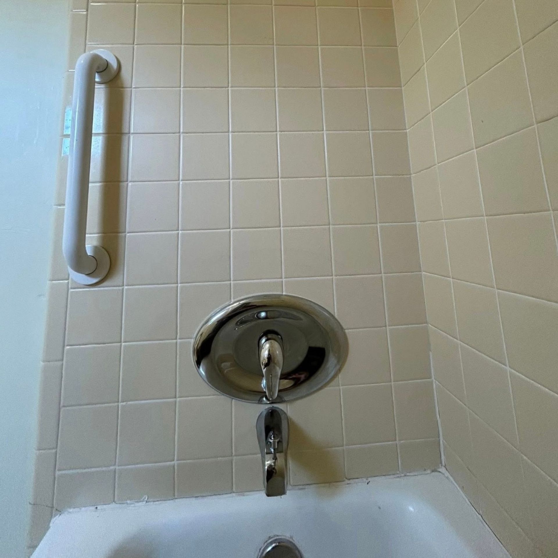 Black River Plumbing & Gas LLC -Bathroom with white tiles, a silver faucet, and a white grab bar.