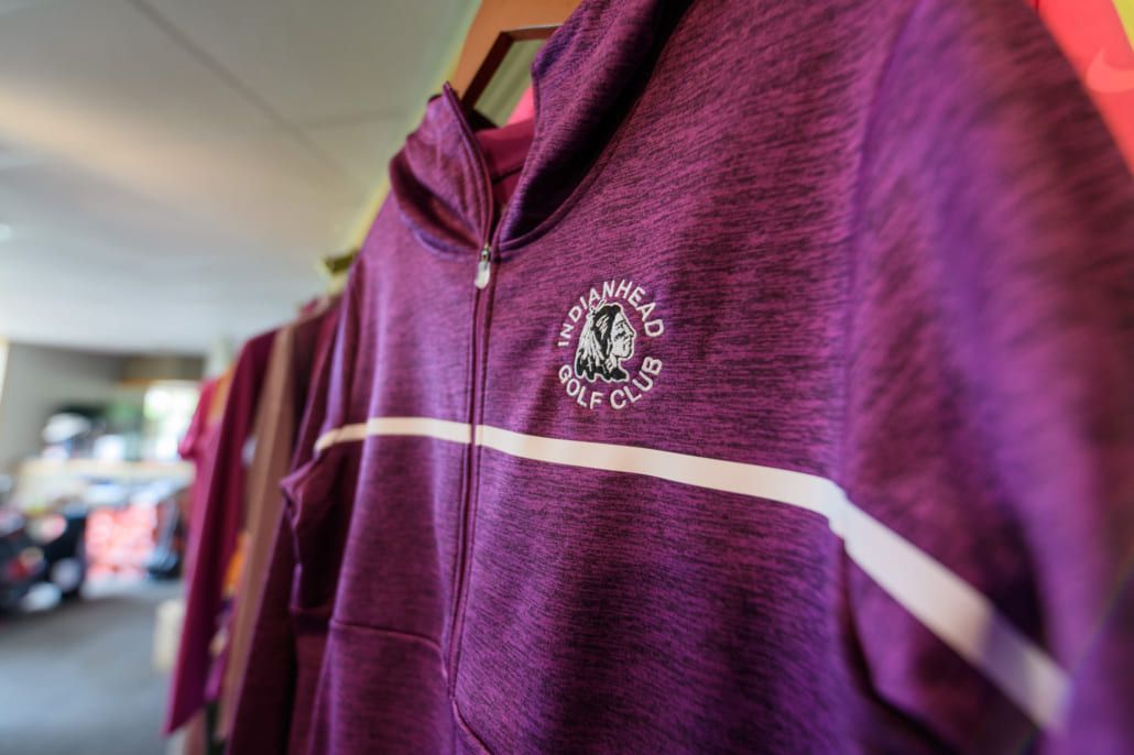 A purple hoodie is hanging on a hanger in a store.