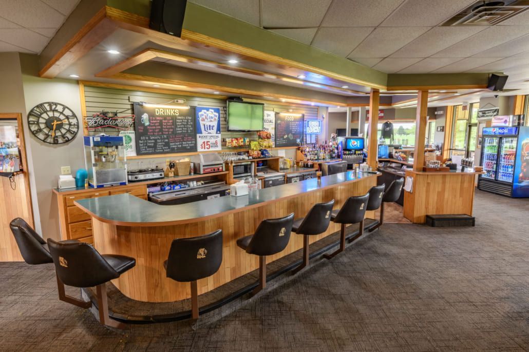 A long wooden bar with stools in a restaurant.
