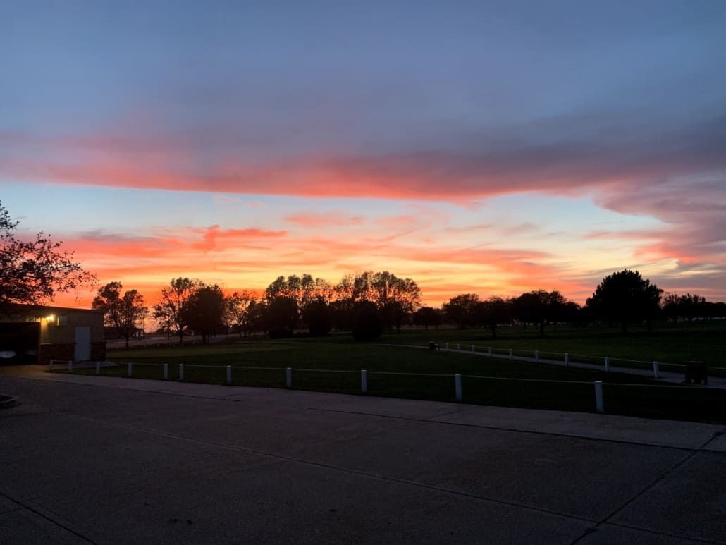 A sunset over a field with trees in the foreground