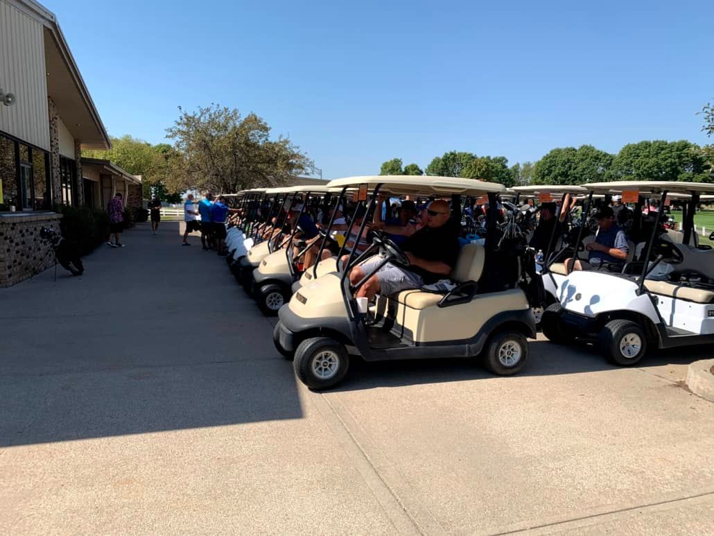 A row of golf carts are parked in a parking lot