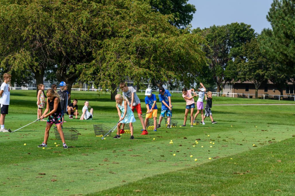 A group of children are playing golf on a golf course.