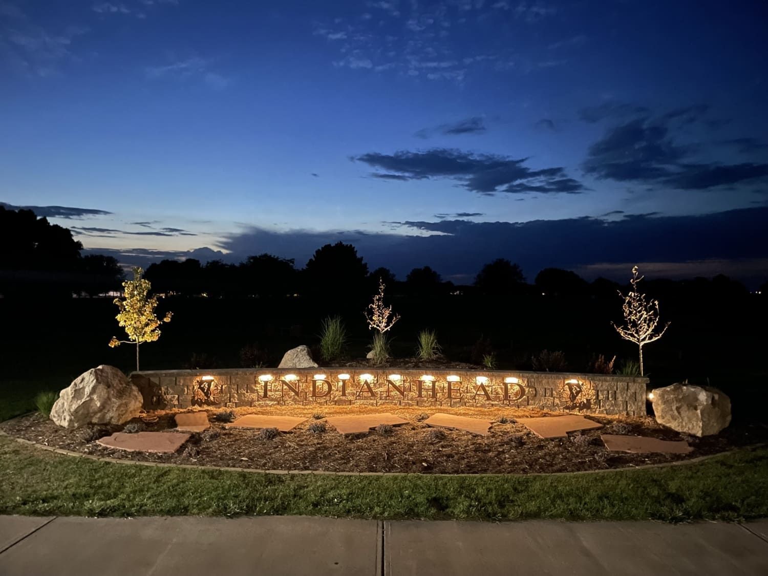 A stone wall with lights on it is lit up at night.