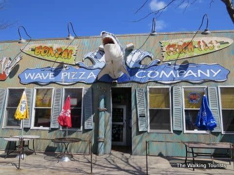 The wave pizza company has a shark statue on the front of the building.