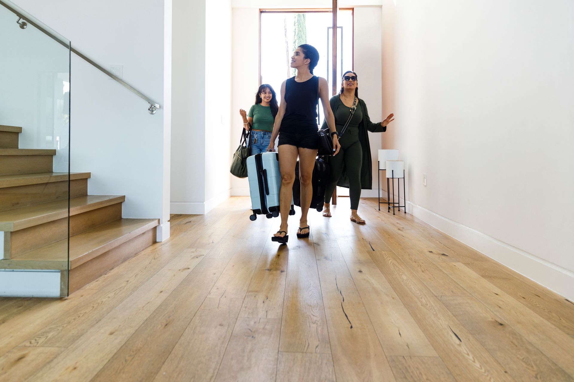 A group of women are walking down a hallway in a house.