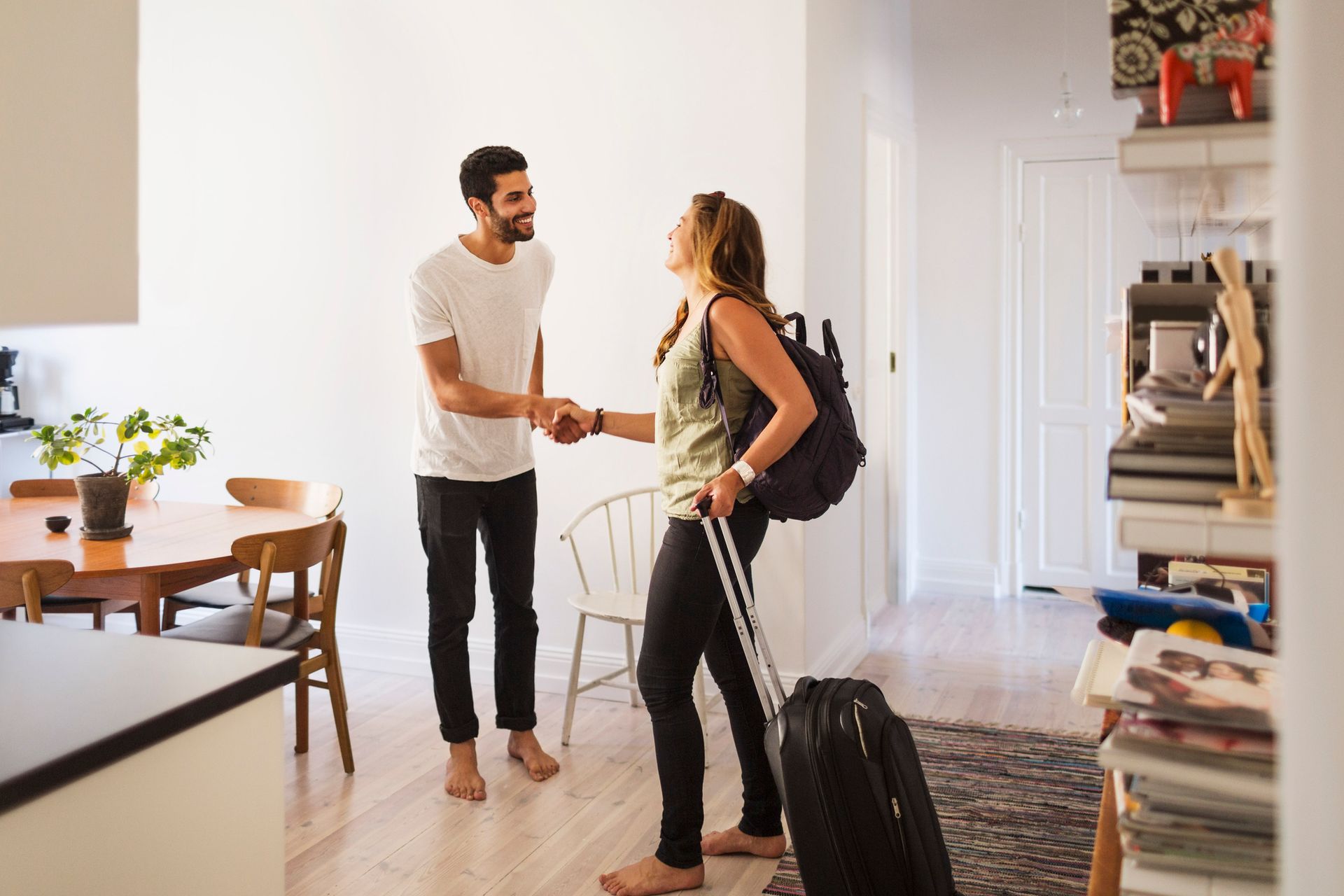 A man and a woman are shaking hands in a living room.