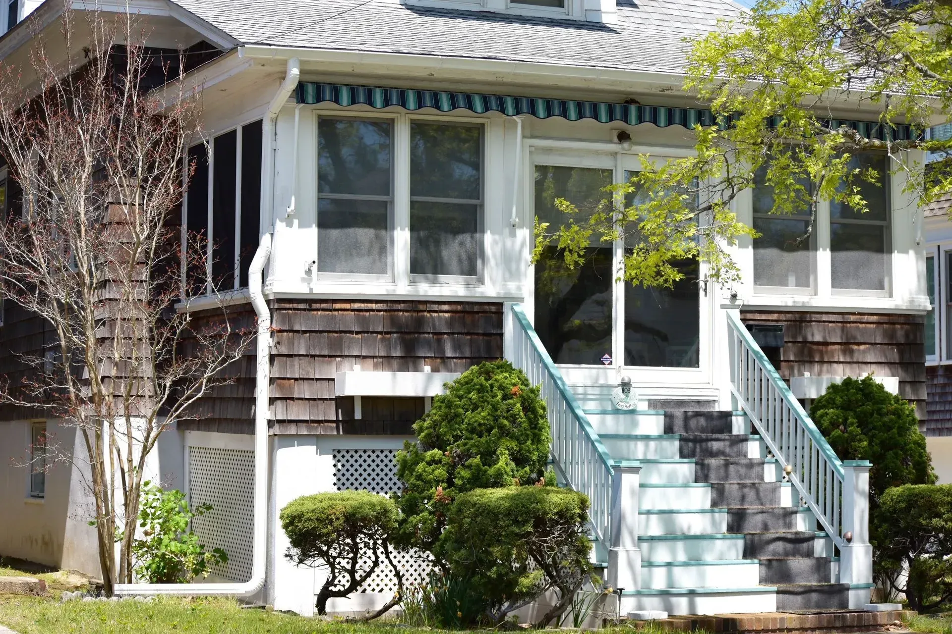 House exterior with shingle siding, porch with awning, white steps with teal accents.