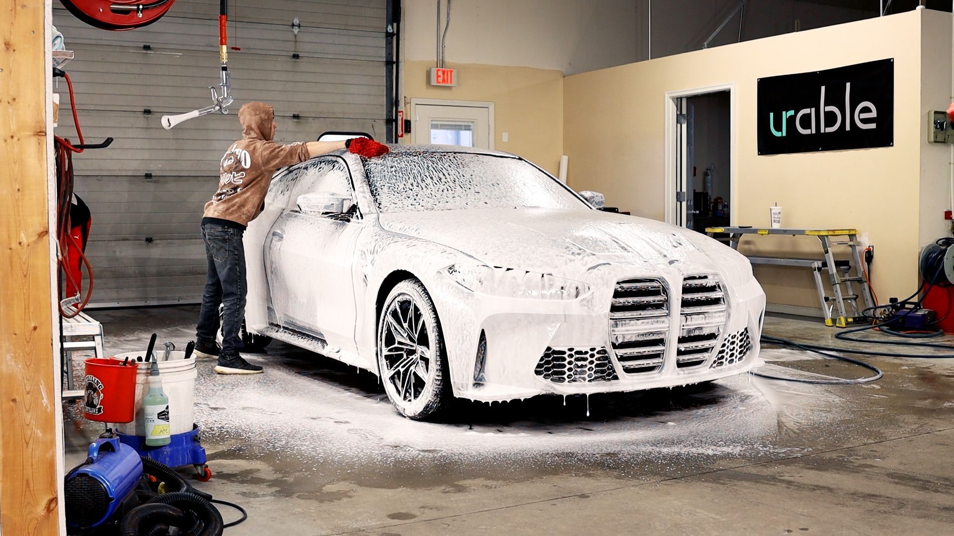 a man is washing a car with foam in a garage .