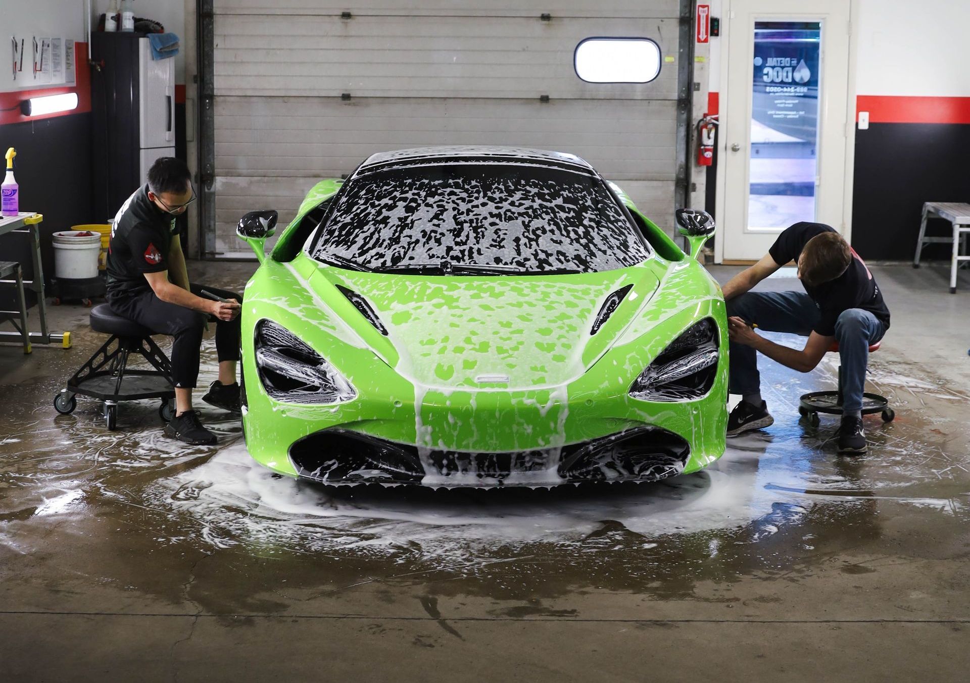 A man is washing a car with foam in a garage.