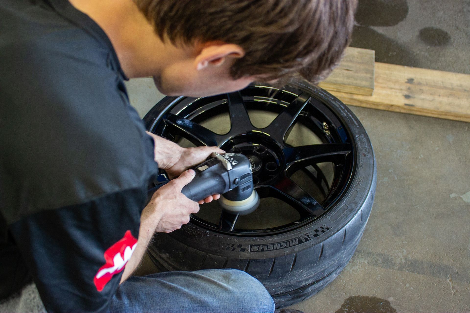 A man is applying protective film to the hood of a car.