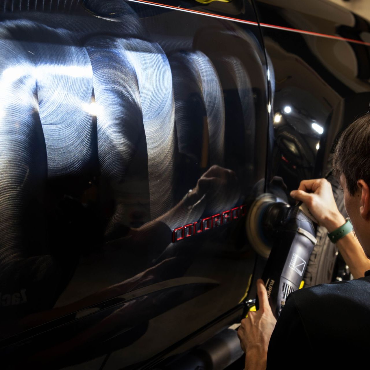 A man is polishing the side of a black car