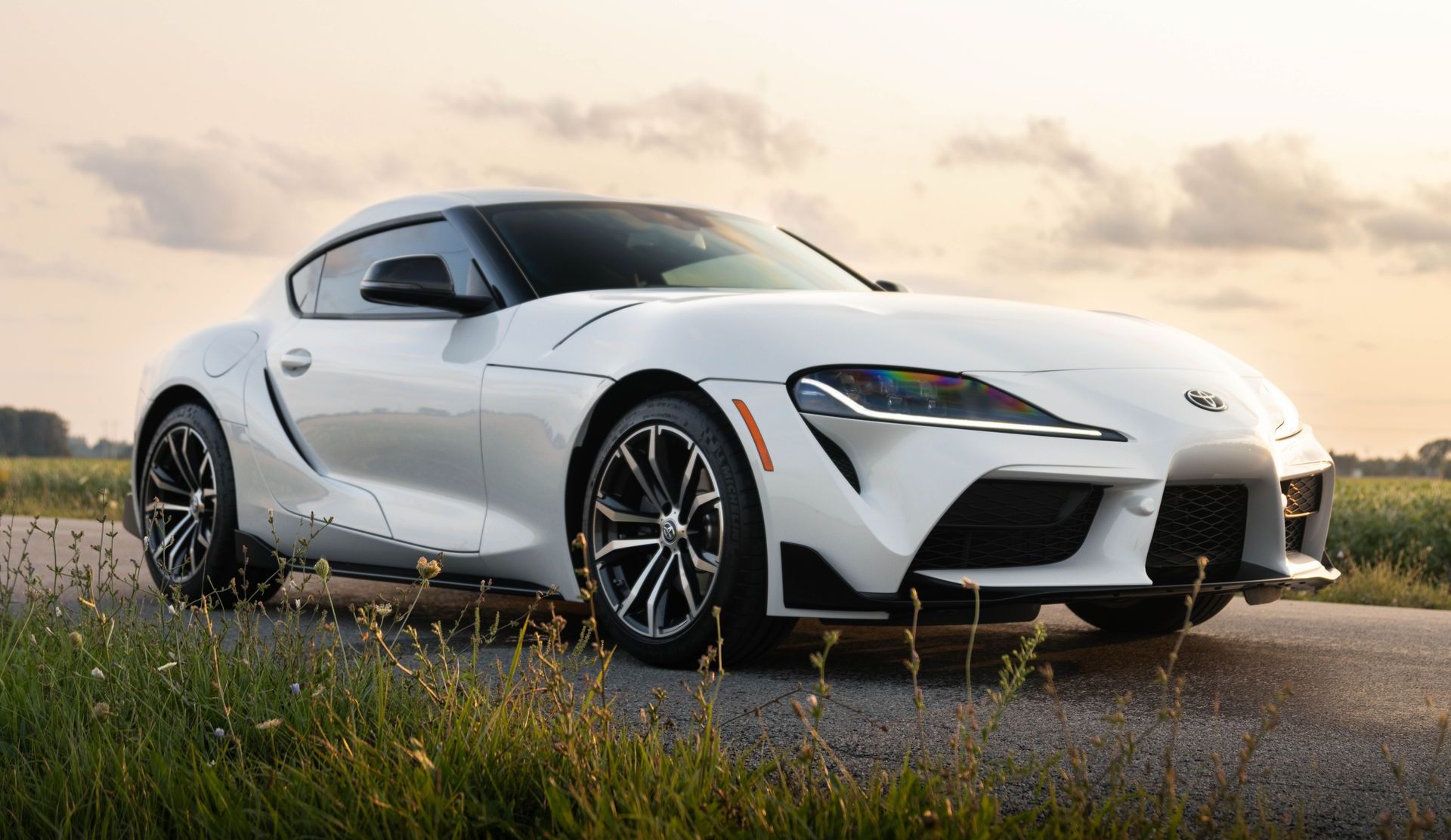 A white toyota supra is parked on the side of a road.