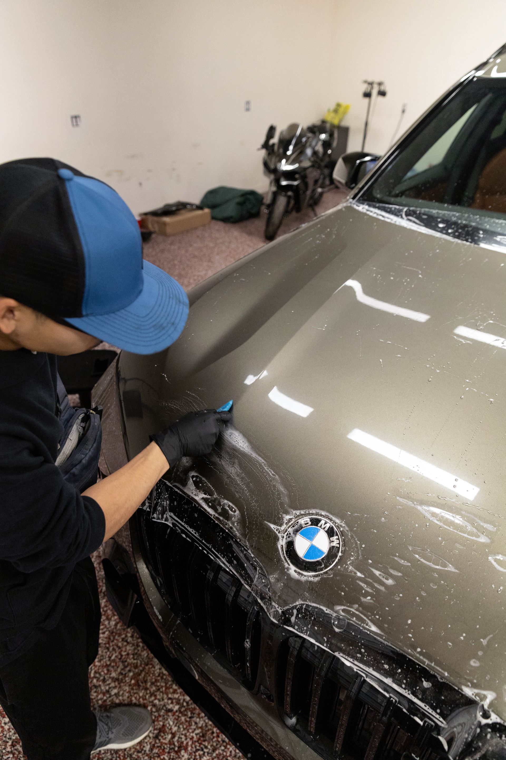 A blue sports car is parked in front of a building that says detail doc