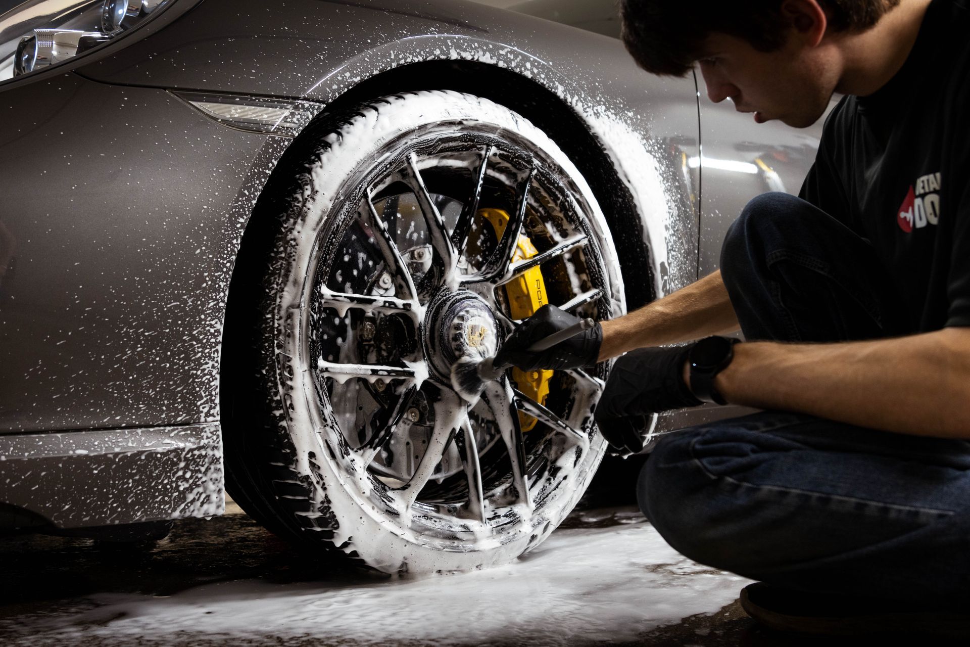 A man is applying a protective film to the side mirror of a car.