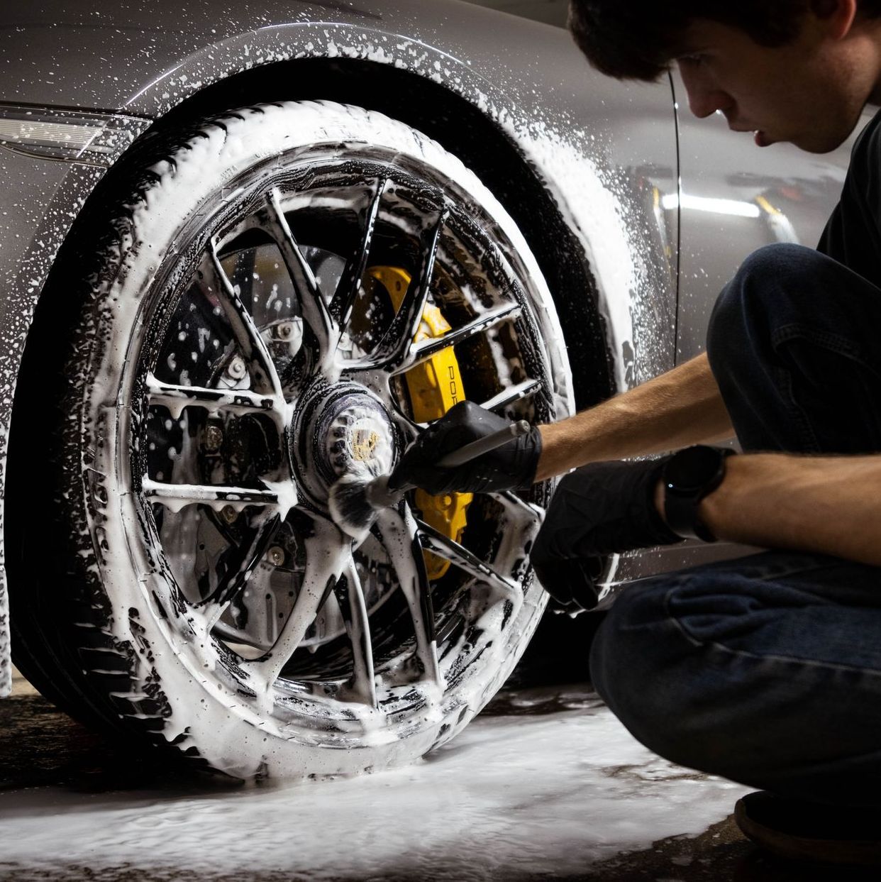 A man is cleaning a car wheel with soap