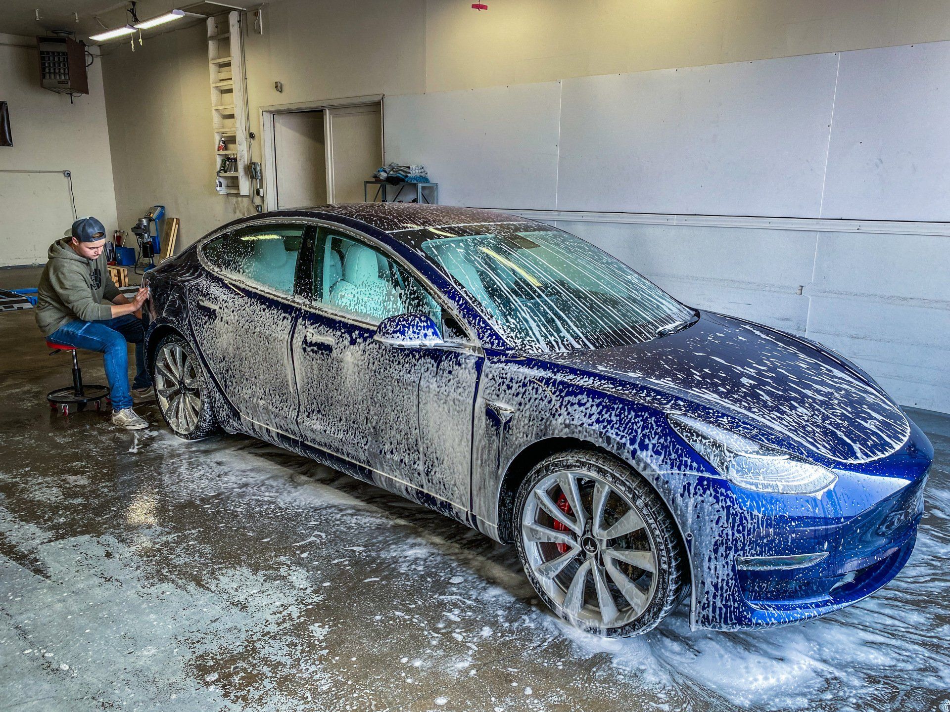 a man is washing a tesla model 3 in a garage .