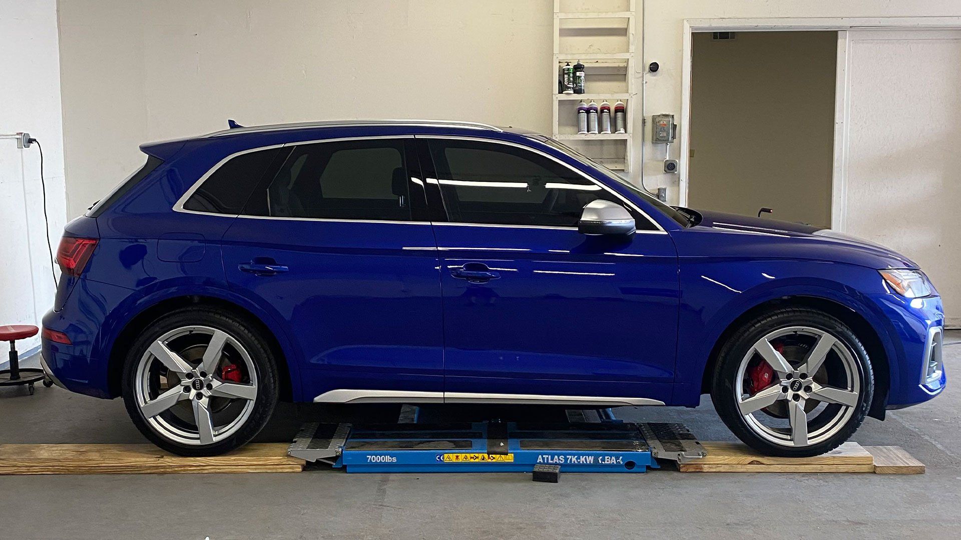 a blue car is sitting on a wooden platform in a garage .