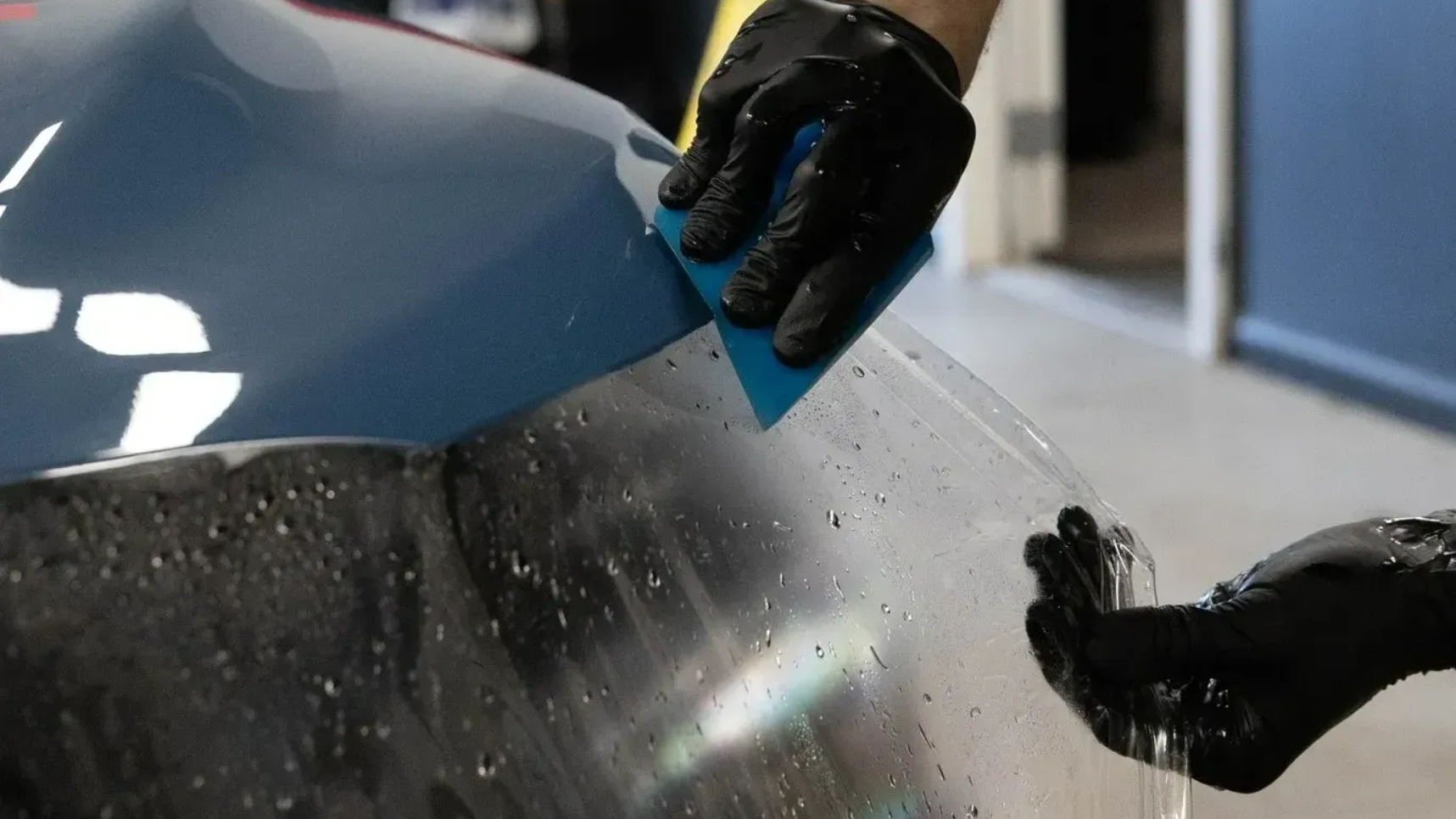 a technicial applying ppf on a blue car