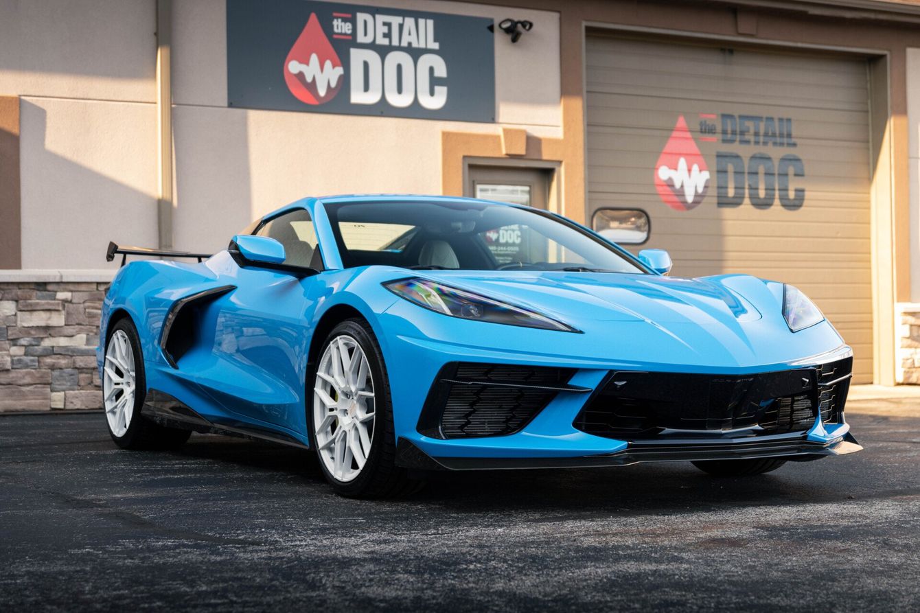 a blue sports car is parked in front of a building that says detail doc