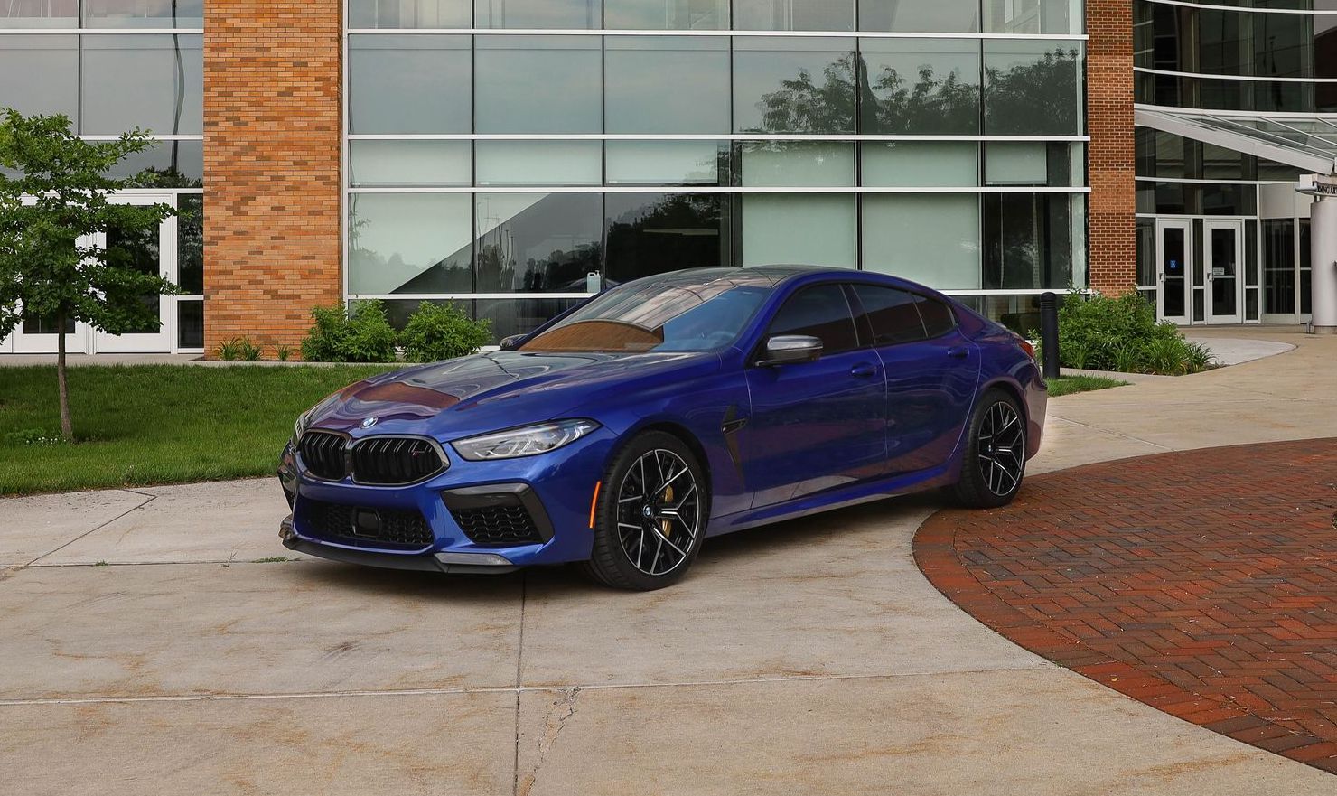 a blue bmw m8 is parked in front of a building .