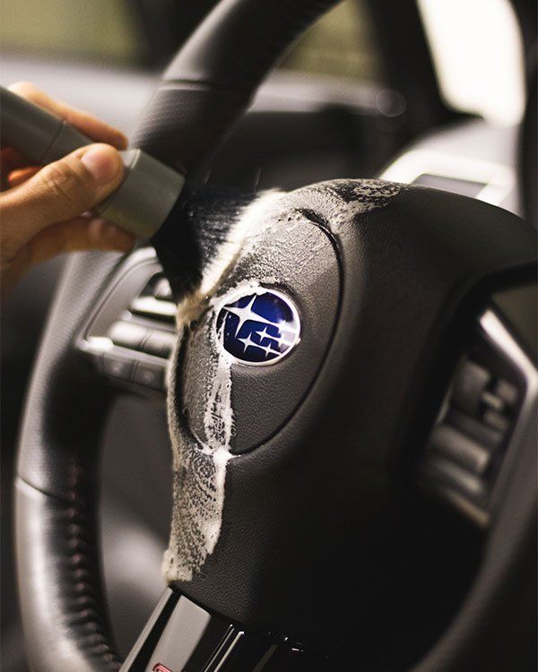 a person is cleaning a subaru steering wheel with a brush