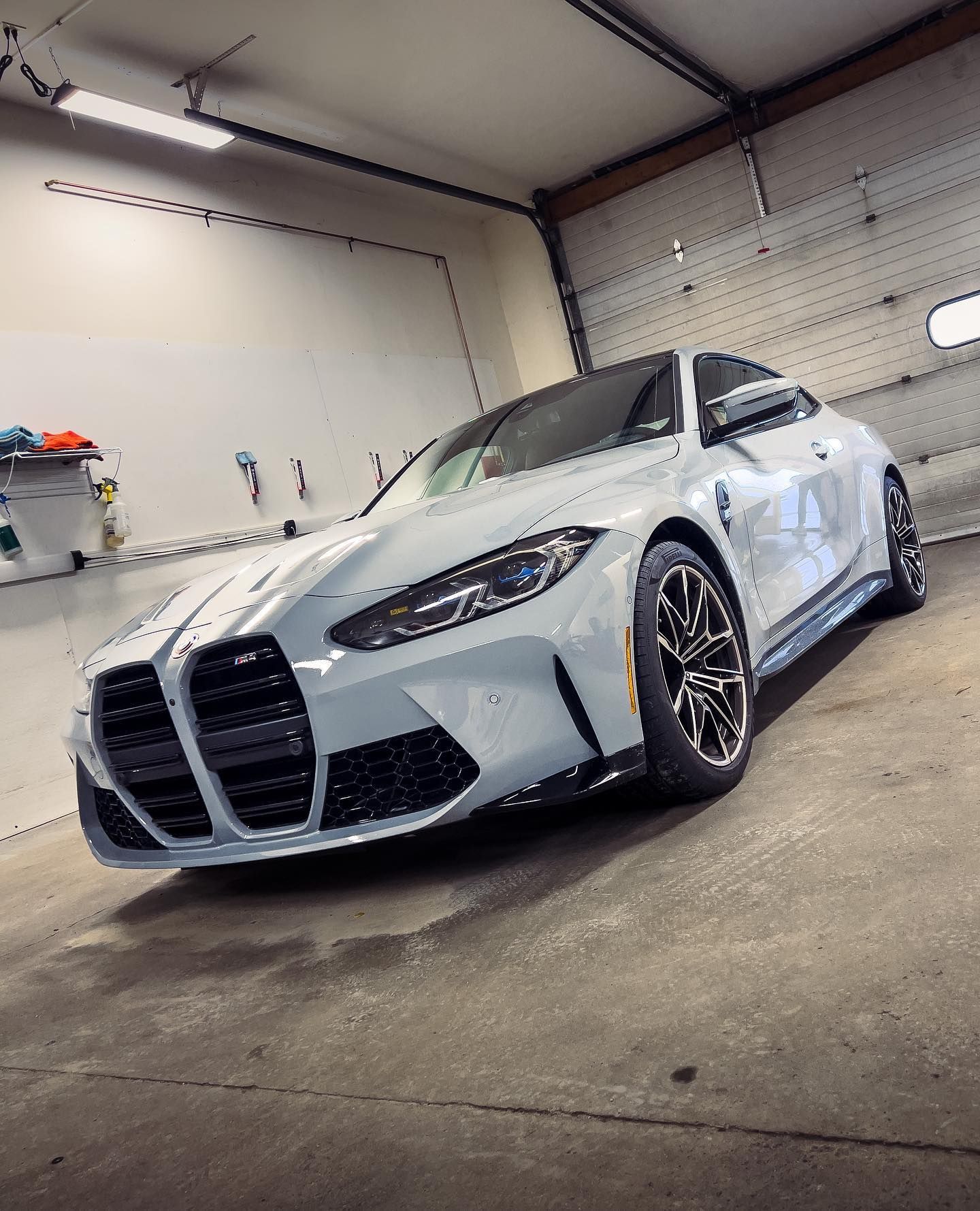 A white bmw m4 is parked in a garage.