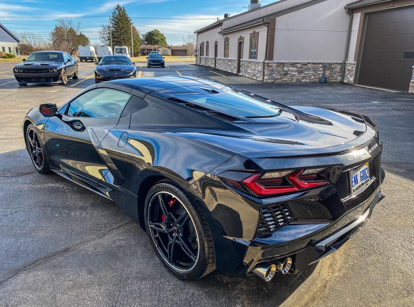 A black sports car is parked in a parking lot in front of a building.