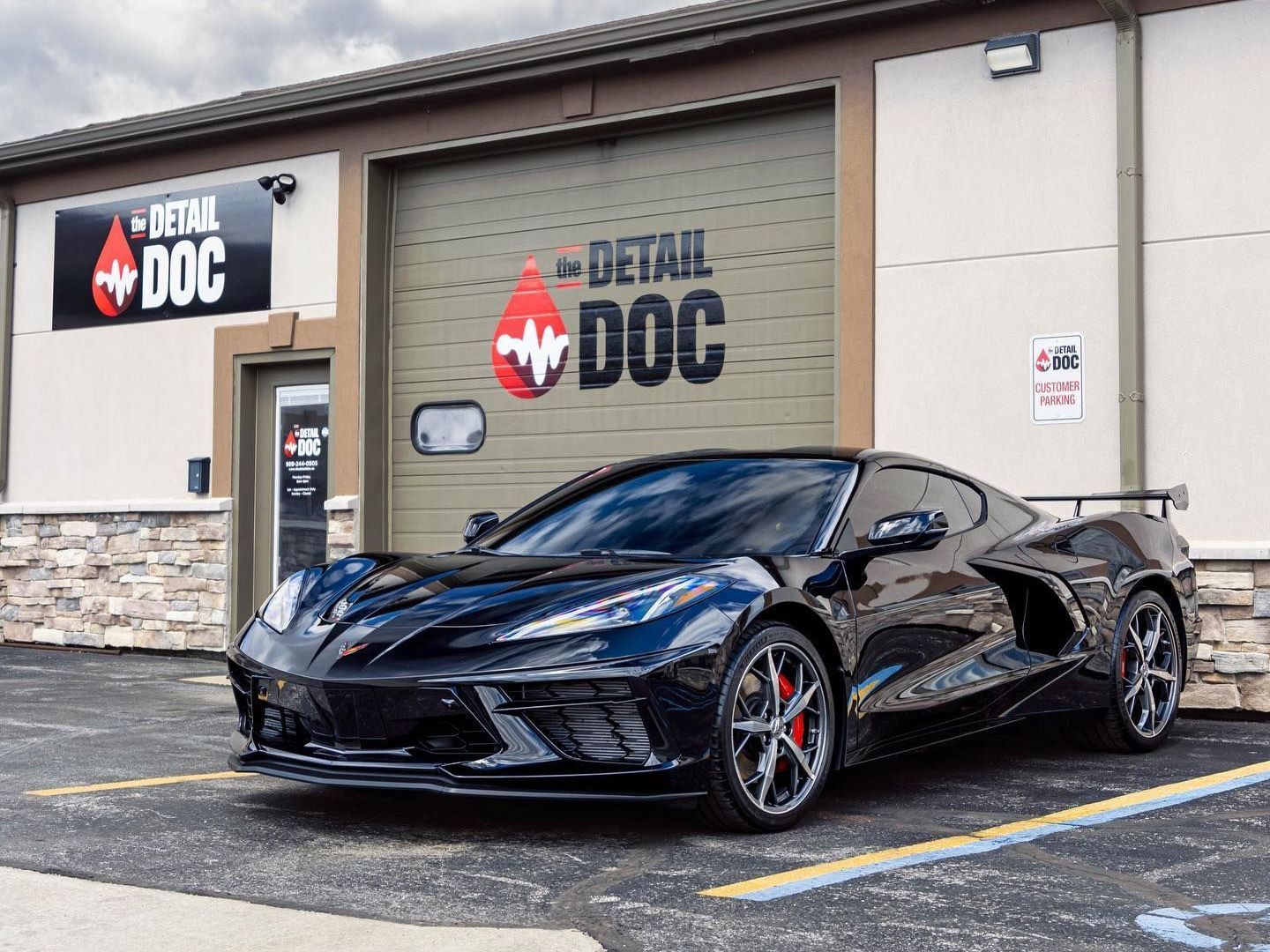 A black corvette is parked in front of a building.