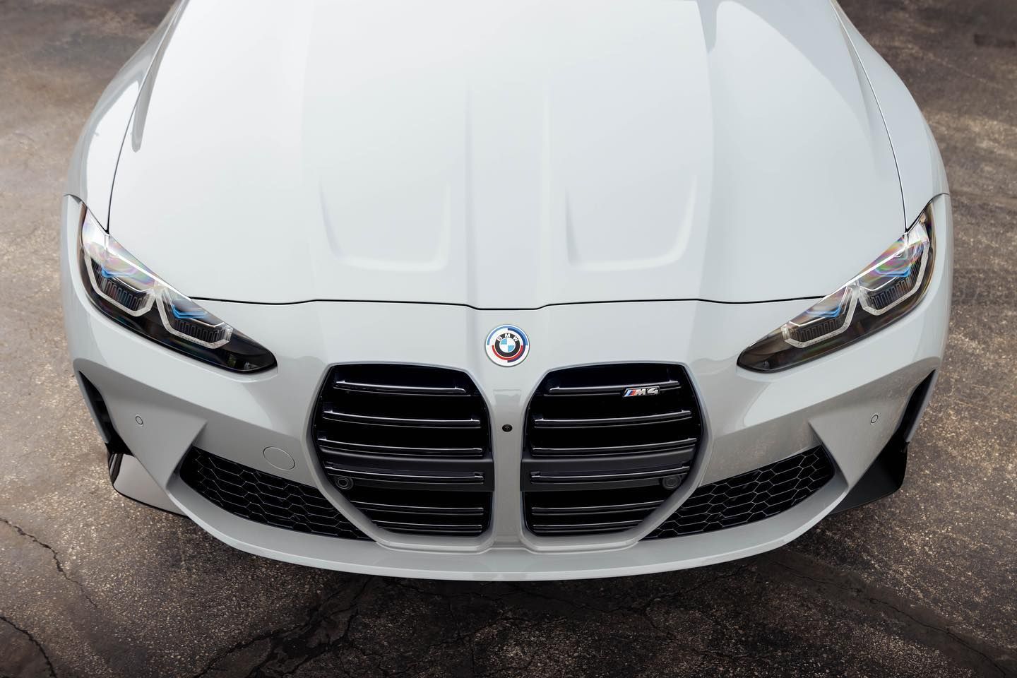 a white bmw m4 is parked on the side of the road .