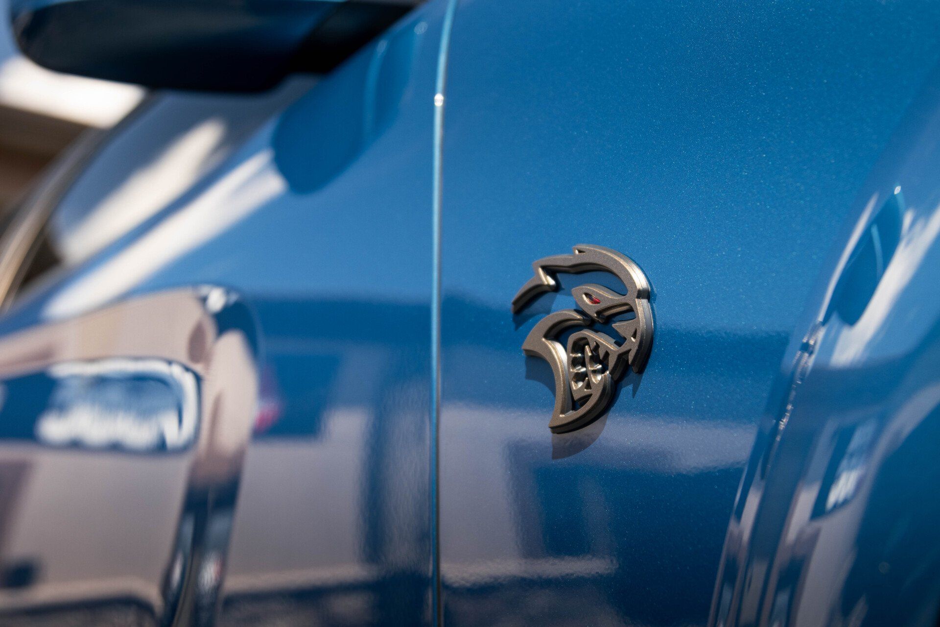 A close up of the side of a blue dodge charger srt hellcat.