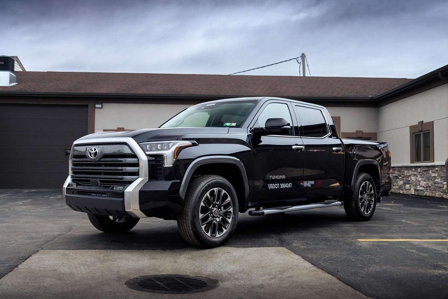 A black toyota tundra is parked in a parking lot in front of a building.