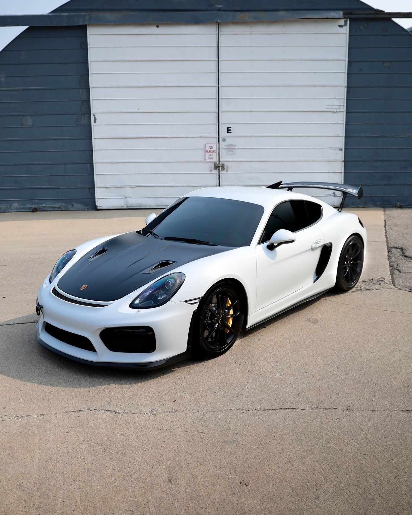 A white porsche 911 gt4 rs is parked in front of a garage.