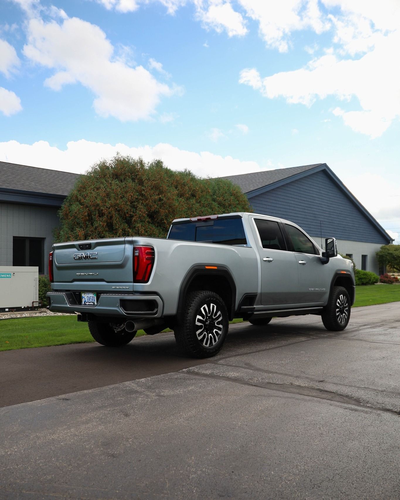 a silver gmc truck is parked on the side of the road in front of a house .