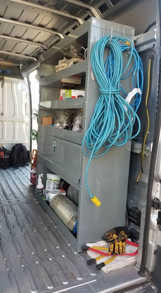 A van with shelves and drawers and a blue hose hanging from the side.