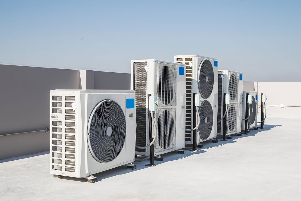 A row of air conditioners are lined up on a roof.