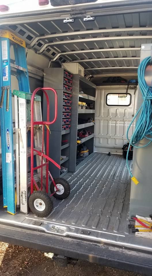 The inside of a van filled with tools and a ladder.