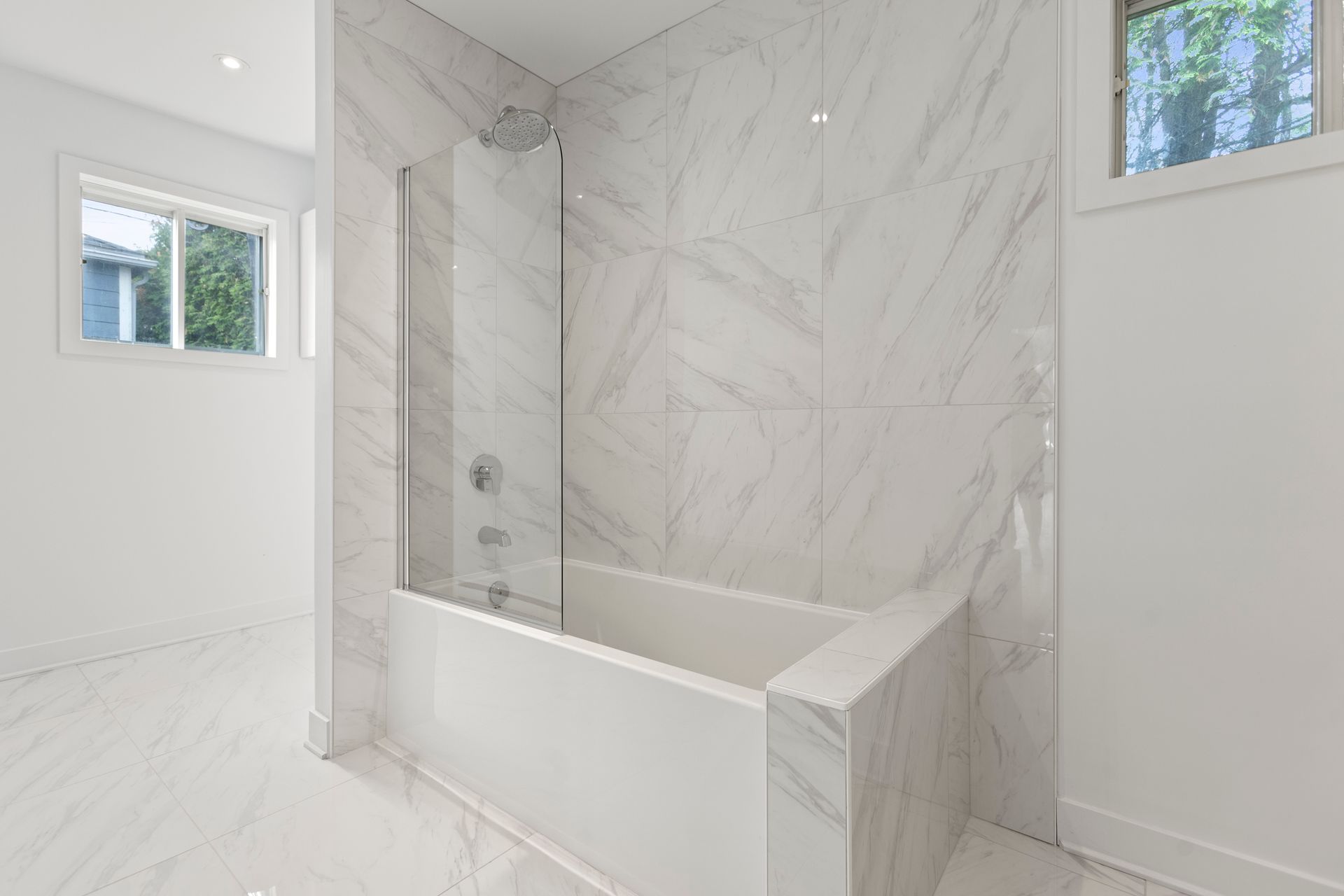 Une salle de bain blanche comprenant une baignoire, une douche avec cabine en verre et des murs à motifs de marbre.