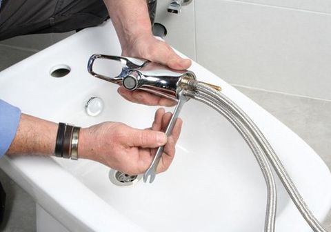 Plumber installing new faucet in bathroom 