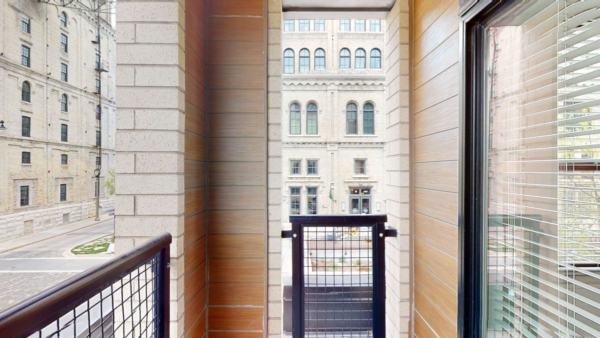 Here at Vim + Vigor Lofts in Wisconsin. A private balcony features warm wood-style walls, city views, metal railing, and convenient access from the apartment.