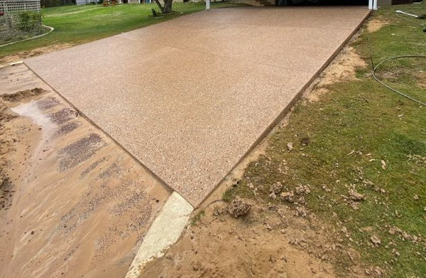 Construction worker using a jackhammer on pavement. Orange cones, cables, and rubble are visible.