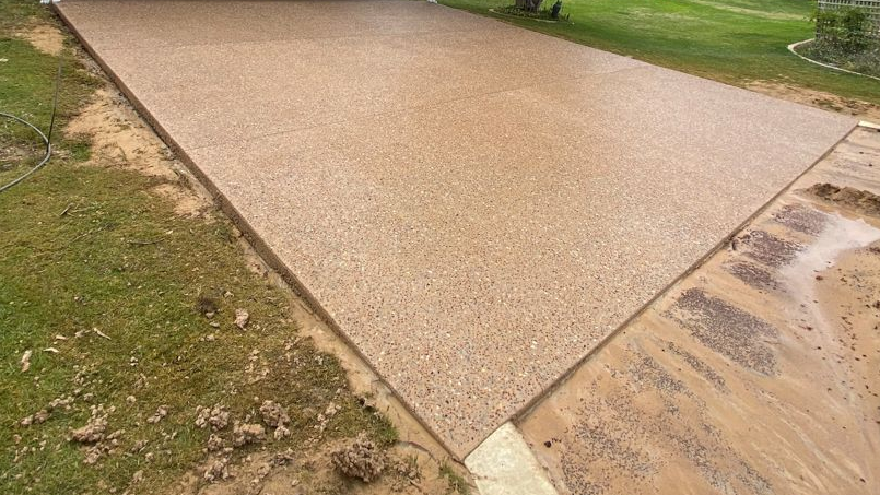 Construction worker using a jackhammer on pavement. Orange cones, cables, and rubble are visible.